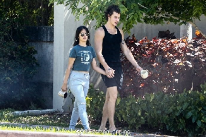 萌德和女友卡妹街头散步,手牵手秀恩爱,手里依旧拿着马克杯