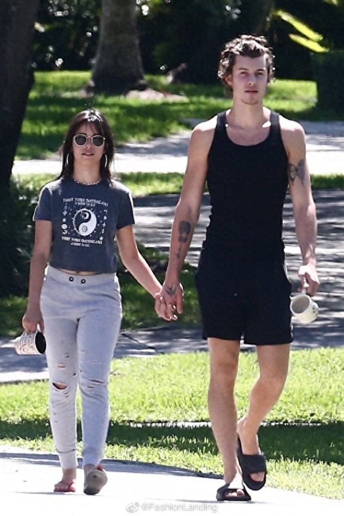 萌德和女友卡妹街头散步,手牵手秀恩爱,手里依旧拿着马克杯